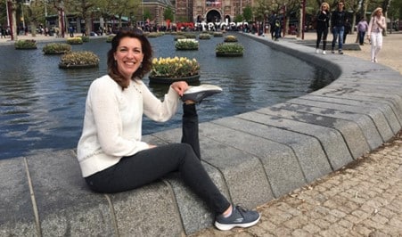 Allison Miller sitting near a fountain holding her prosthetic leg