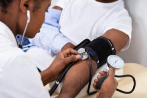 Close-up Of Doctor's Hand Measuring Blood Pressure Of Male Patient