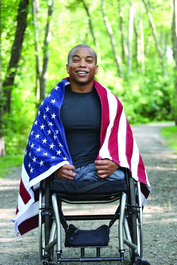 young amputee in wheelchair with american flag