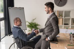job candidate in wheelchair shakes hand with interviewer