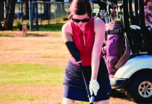 Woman playing golf wearing adaptive upper-limb prosthesis.