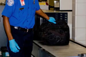 TSA agent reaches for a bag which has just been scanned 