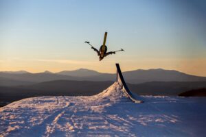 Trevor Kennison does a backflip on a sit ski off a mountain.